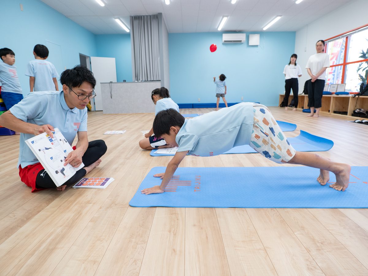 トレーナーが子どもたちに丁寧に指導している様子